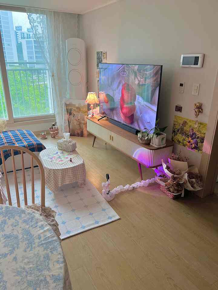 ナチュラルな木目調とベージュのリビング、テレビ台やカーテン、おしゃれなホームカフェテーブルとラグが配置された雰囲気のあるインテリア