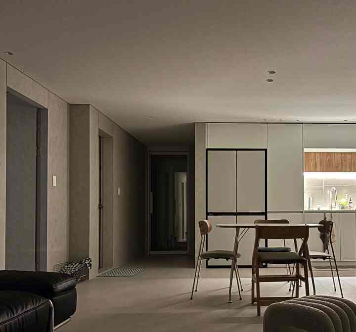 落ち着いたホワイトとブラウンのトーンの対面式キッチン、ダイニングテーブルと椅子が配置されたモダンで自然な雰囲気のインテリア