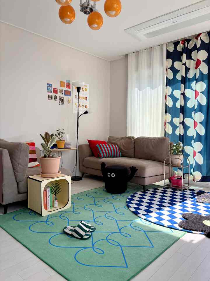 ナチュラルカラーとブルーの色調が特徴のリビング、ソファやラグ、カーテン、フロアランプが配置された雰囲気のあるインテリア