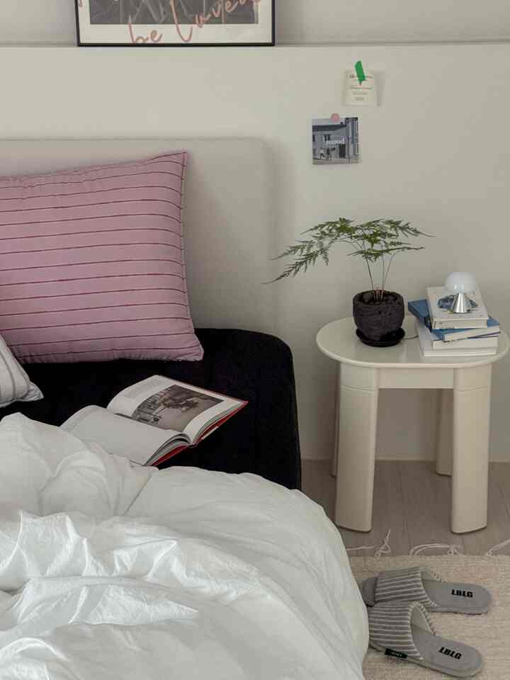White and black toned bedroom featuring a white stool and pink cushion, creating a cozy atmosphere