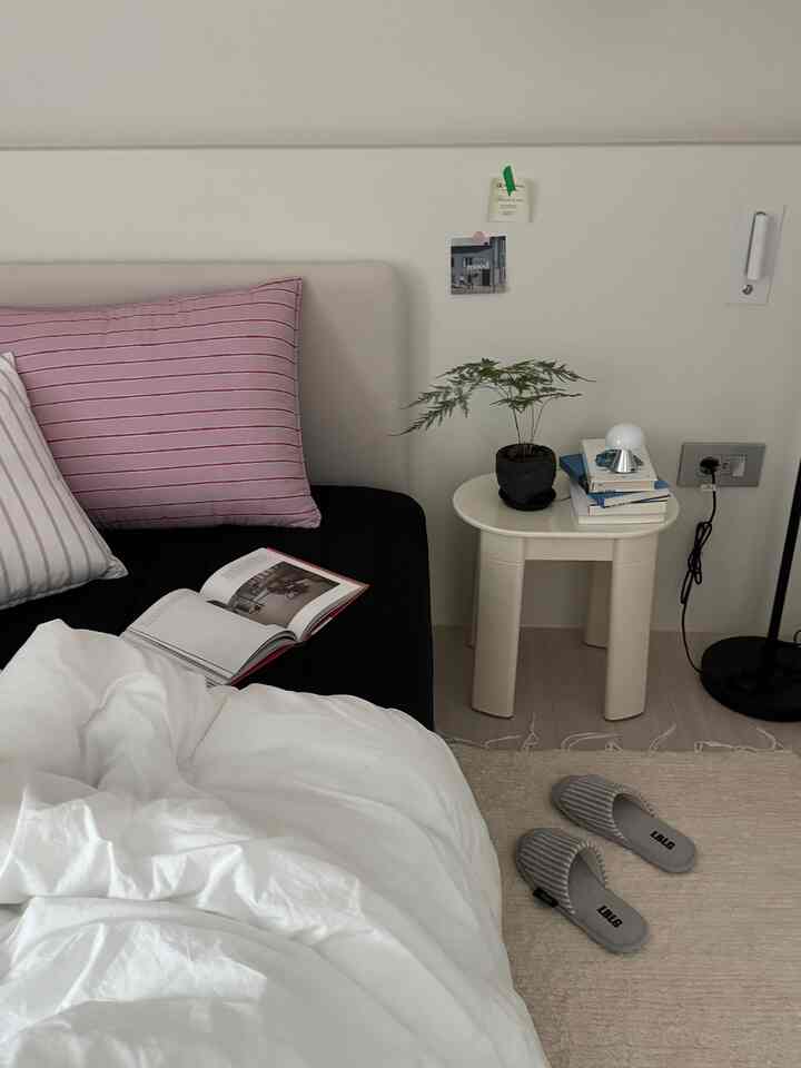 White and black tone bedroom featuring black bedding and pink pillows in a simple, modern setting
