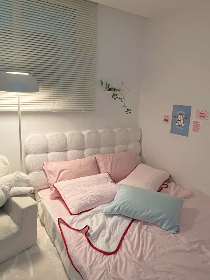 白とピンクの色調の子供部屋寝室、居心地の良いクッションと柔らかな照明が配置された印象的な空間
