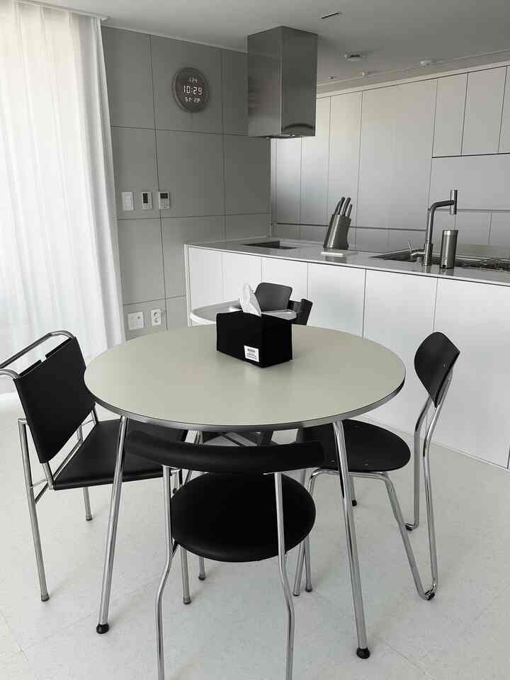 Monotone kitchen in white and gray featuring a round dining table with black chairs, creating a clean and spacious atmosphere