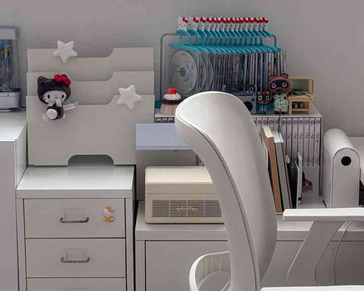 白を基調とした小さなホームオフィス、シンプルなデスクと椅子、整理された収納家具が配置された清潔感のあるコレクションスペース