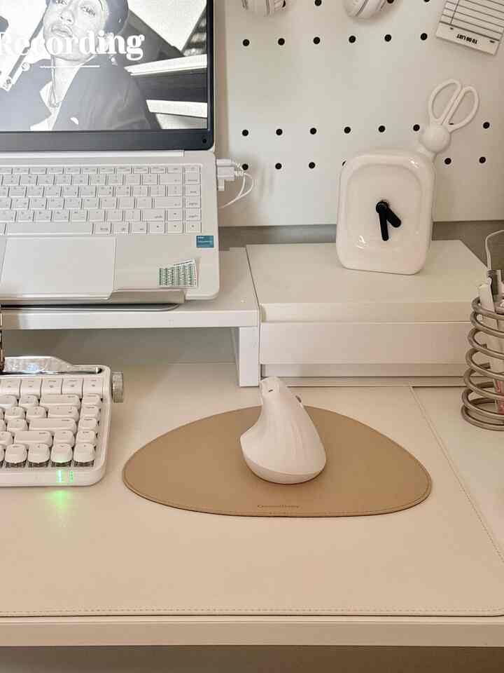 White and beige toned home office desk featuring ceramic clock and ergonomic mouse in neat workspace