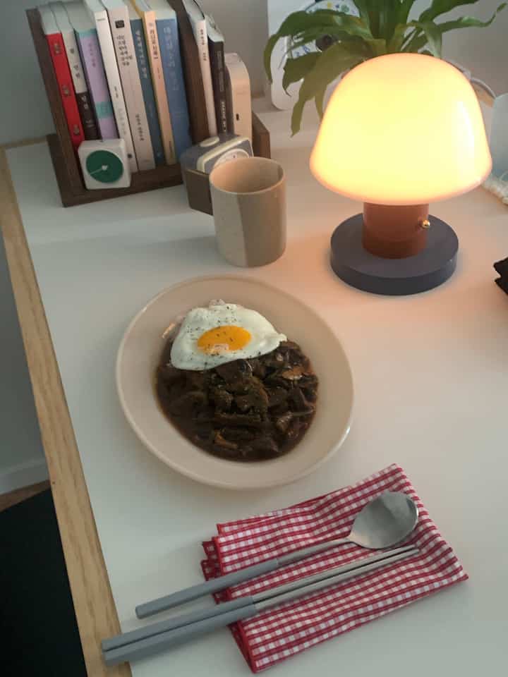 暖かいオレンジ色のテーブルランプと白いデスクが配置された北欧風のおうちカフェの雰囲気あるインテリア