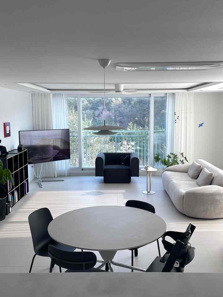 白と黒のトーンのモダンなリビングルーム、円形のダイニングテーブルと多様なソファが配置された印象的な空間