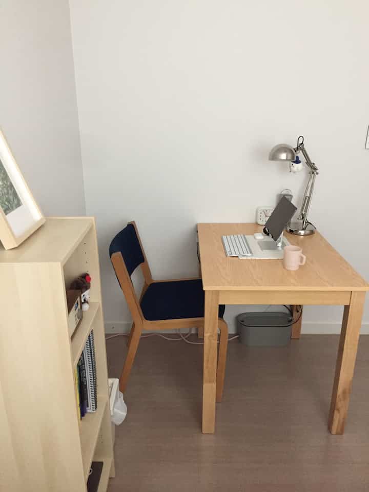 白とナチュラルウッド調の小さなホームオフィス、シンプルモダンな机とネイビーチェアが配置された落ち着いた雰囲気のインテリア