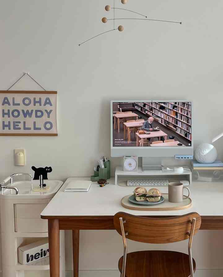 White walls and brown wooden desk featuring a computer and simple meal set in a clean, natural home office space