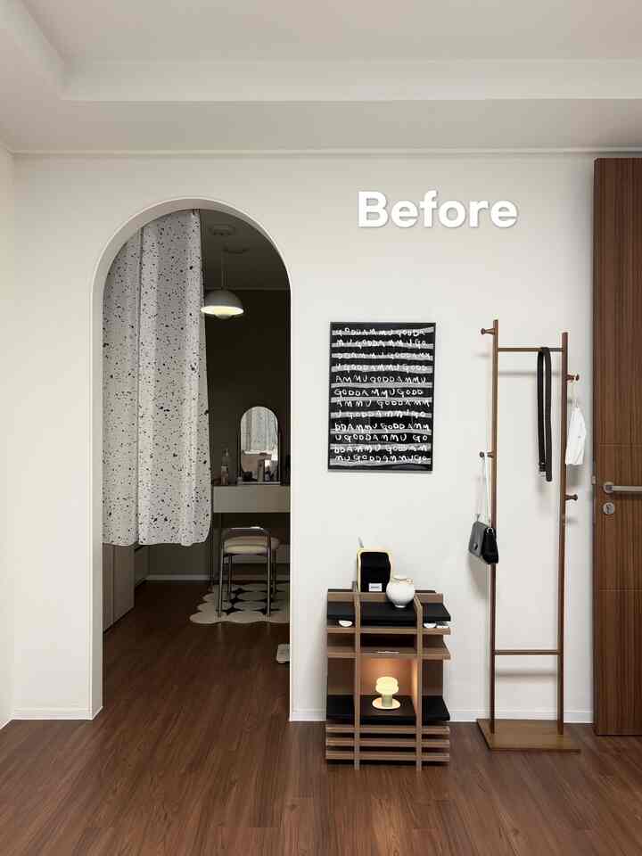 白い壁と木目調の床があるワンルーム玄関、シンプルな家具と衣服掛けが配置されたミニマルなインテリア