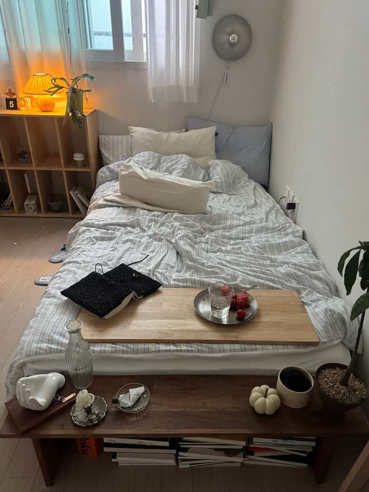 明るいホワイトと木目調が調和したシンプルな寝室、快適なベッドと温かみのある照明が配置された自然な雰囲気のインテリア