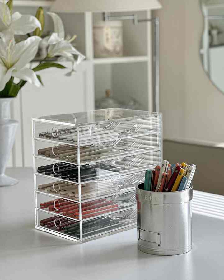 透明なアクリル収納とシルバーの容器にサーブルのカトラリーが整然と並べられた清潔感のあるキッチン空間