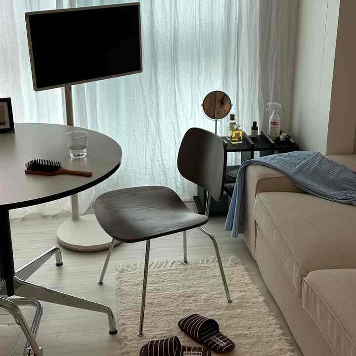 白いカーテンとベージュのソファがあるすっきりとした一人暮らし用ホームオフィス兼リビングスペース