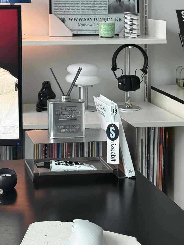 黒とシルバーのトーンのデスクスペース、マーシャルのブルートゥースヘッドホンとディフューザーが配されたシンプルモダンなホームオフィスのインテリア