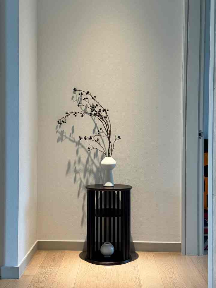 Minimalist entrance space in white and black tones featuring decorative objet with round side table in a modern clean interior