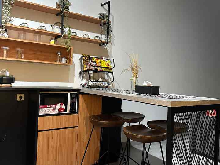 Wood tone and black themed kitchen featuring wooden counter stools and open shelves with a neat and stylish atmosphere