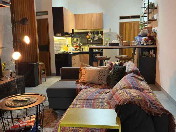 Wood tone and black combined living room and kitchen featuring colorful cushions and rug, creating a cozy interior