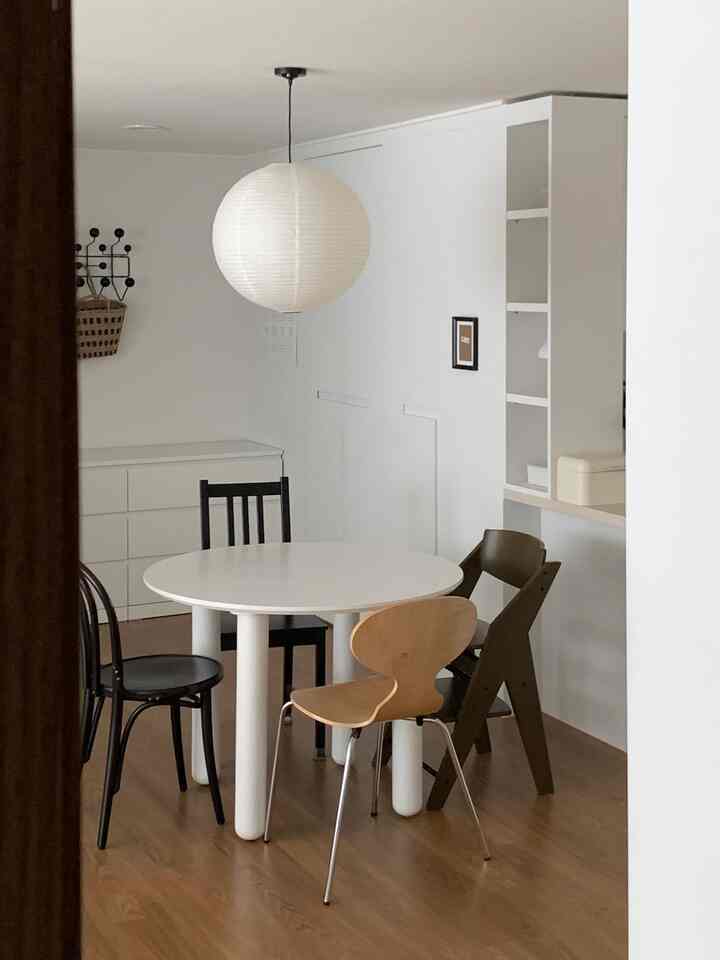 白を基調としたキッチンスペース、丸いダイニングテーブルと異なるデザインのチェアが調和したシンプルでナチュラルなインテリア