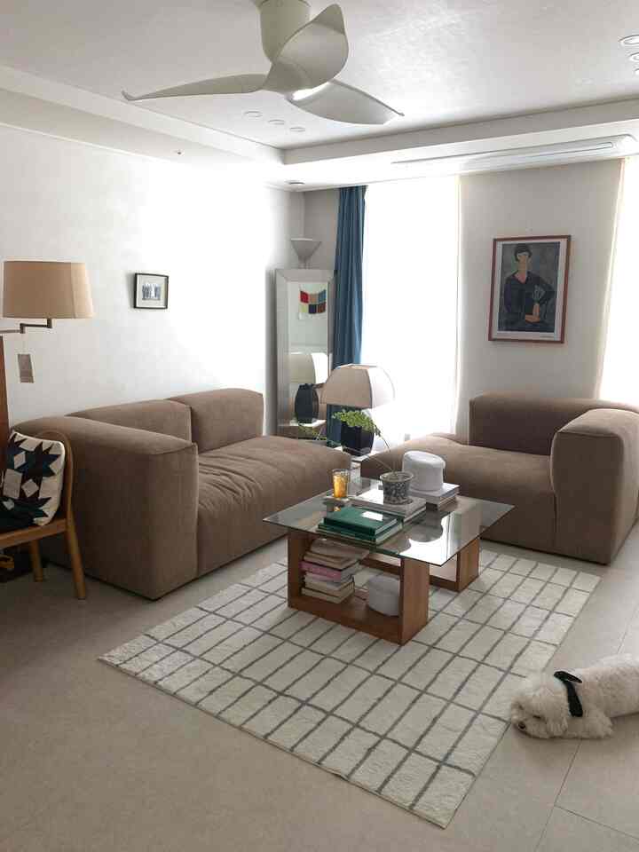 白とベージュのトーンのリビング、2つのソファとガラスのコーヒーテーブルが配置された落ち着いた雰囲気のインテリア