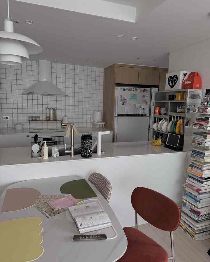 白と茶色のトーンのキッチンとダイニング、書籍とテーブルが配置された居心地の良いコンパクトな空間