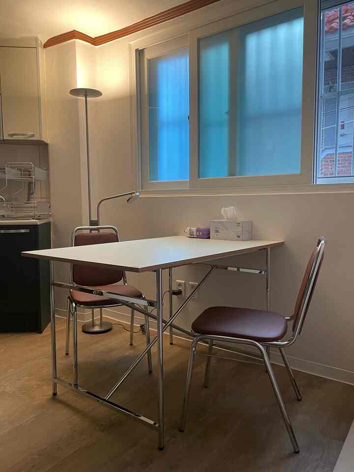 白と茶色を基調としたコンパクトなキッチン兼ホームオフィス、シンプルな家具とフロアランプが配置された落ち着いた雰囲気のインテリア