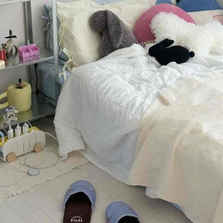 白とベージュの色調の寝室、柔らかい寝具とクッションが配置された居心地の良いインテリア