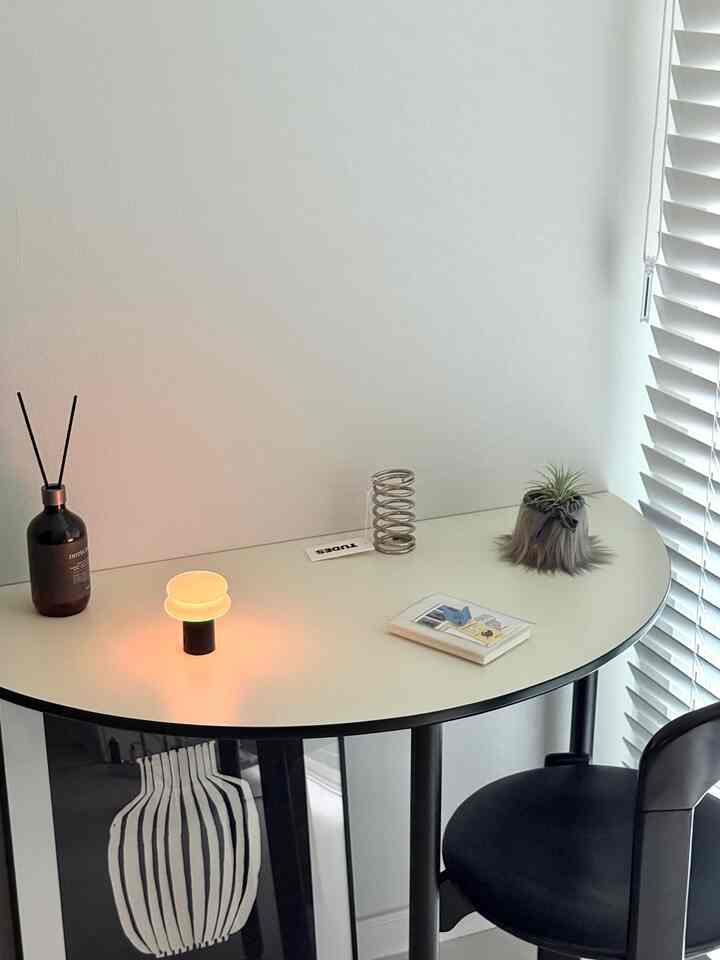 Modern half table space in white and black tones, featuring a small table lamp, a neat plant, and diffuser creating a calm atmosphere