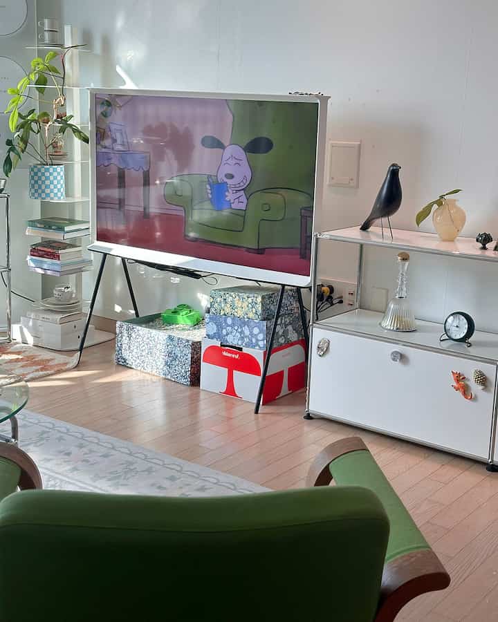 白と緑の色調のリビング、テレビと緑のアームチェアが配置された落ち着いたモダンな雰囲気のインテリア