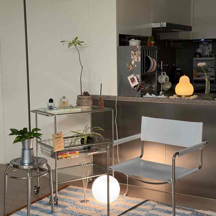 Silver and white toned kitchen space featuring stainless steel kitchen cart and white armchair with a modern, cozy atmosphere