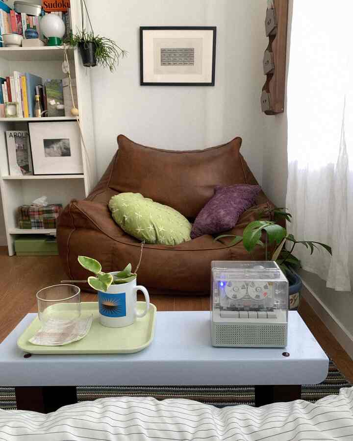 ライトブラウンと木目調が調和する小さなリビング、快適なビーンバッグソファとコーヒーテーブルが配置された雰囲気のある空間