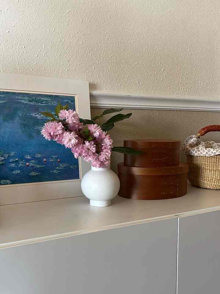 Natural brown and white toned entrance decor featuring a vase with flowers and storage boxes creating a cozy atmosphere