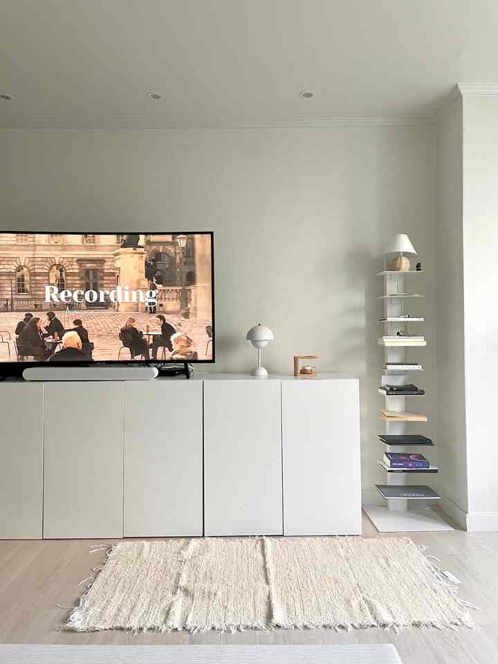 White and beige tone living room featuring a TV stand and shelf with a simple interior design