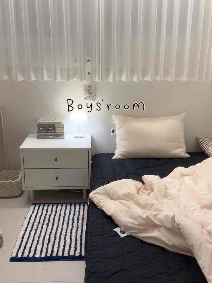 白と黒の落ち着いた色調の子供部屋、シンプルでモダンな雰囲気の小さなチェストと黒いマットレスカバーが配置された印象的な空間