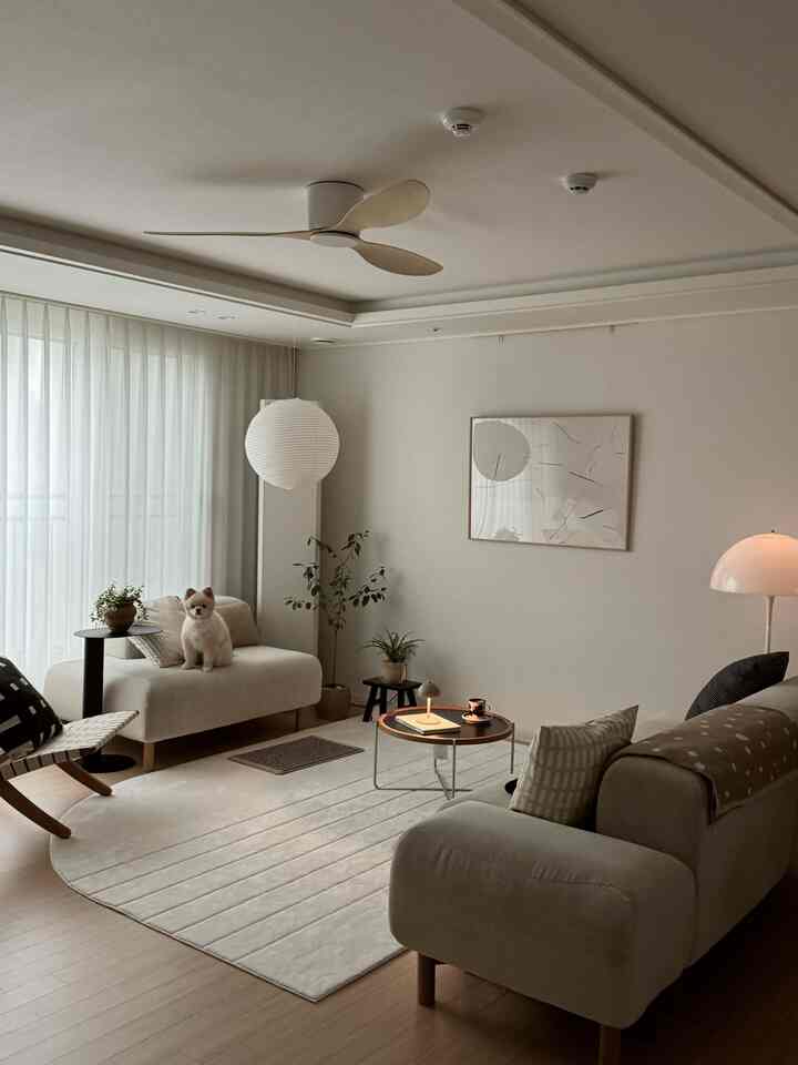 ナチュラルな色調のリビング、犬がいるソファと丸いテーブルが配置された雰囲気のある空間