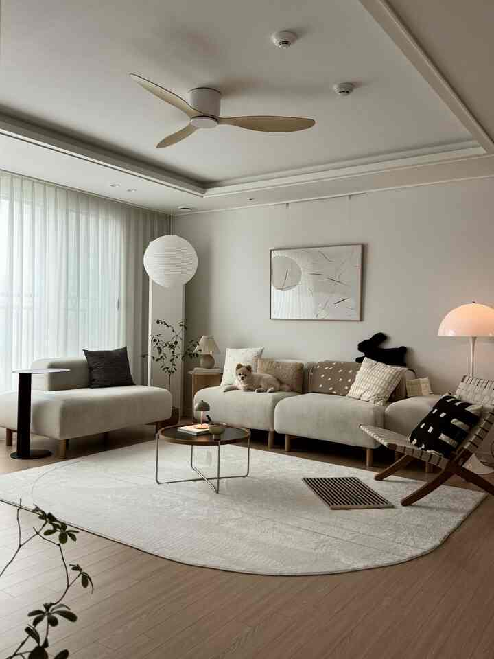 Beige and white toned living room featuring modern sofas and rug with a small pet dog resting comfortably