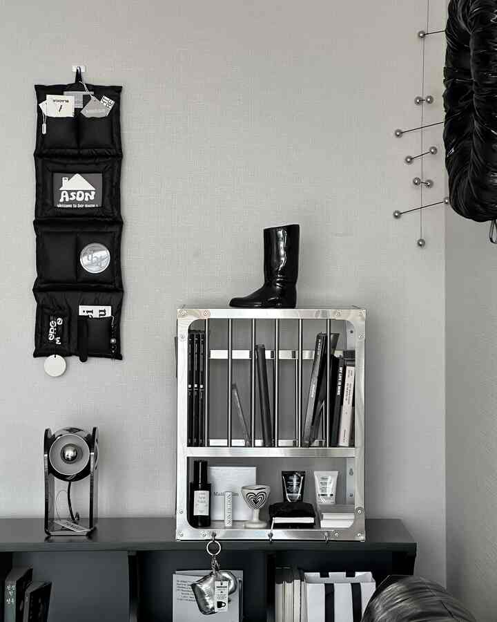 モダンな色調の書斎、黒いレザーソファとメタルシェルフ、ブーツ型花瓶が配置された整ったインテリア