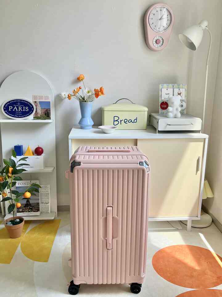 明るいホワイトとベージュの空間、ピンクのスーツケースと花瓶、壁掛け時計が配置された印象的なインテリア