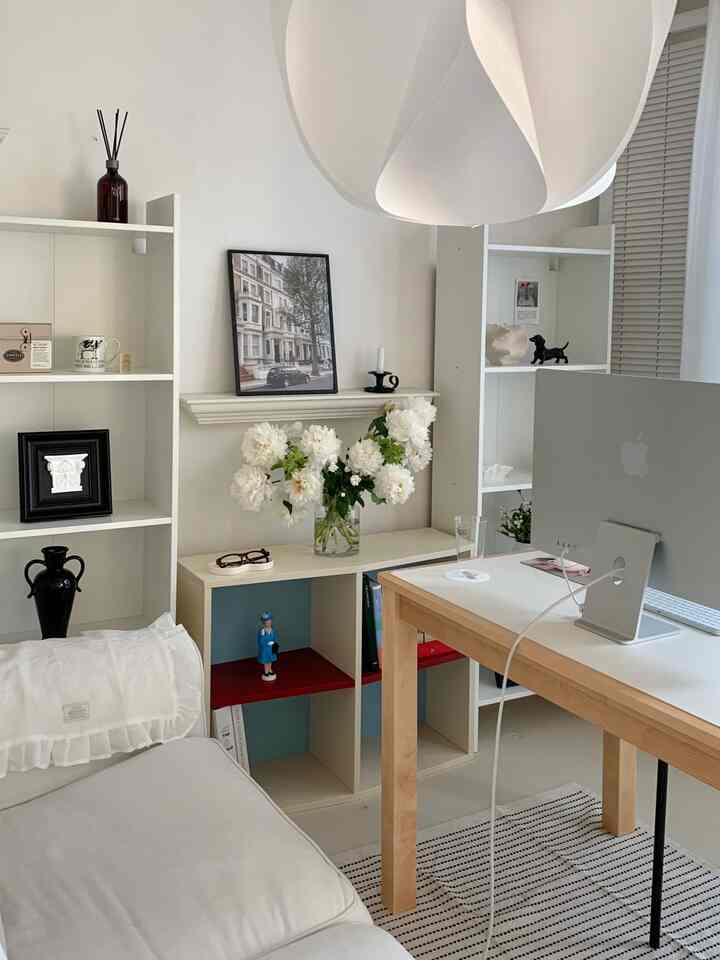 白と木目調が調和したリビング兼ホームオフィス空間、デスクやソファ、飾られた花瓶と額縁が印象的な雰囲気を演出