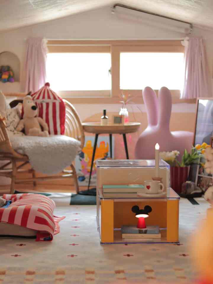 パステル調の子供部屋、ウサギ形のチェアとラタンのアームチェア、玩具が置かれた雰囲気のある空間