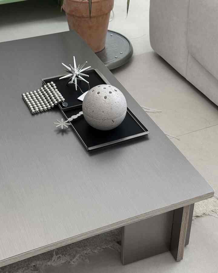 シルバートーンのリビングのコーヒーテーブルにトレイとオブジェが配置された、モダンで清潔感のあるインテリア