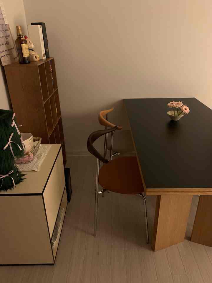 ウッドトーンとブラックが調和したキッチン空間、ブラックトップのダイニングテーブルと木製家具が配置された落ち着いたモダンな雰囲気のインテリア