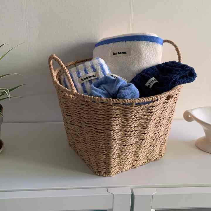 Natural tone basket holding blue-toned towels in a bathroom accessories setup