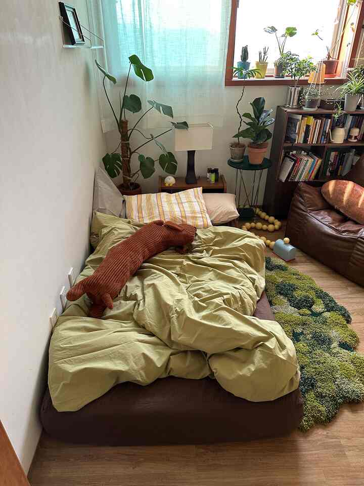 ナチュラルな木目調とグリーンが調和した、寝具と植物が配置された落ち着きのある寝室