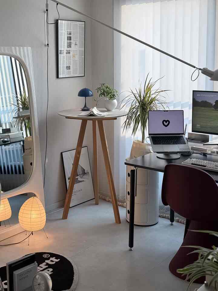 白とナチュラルトーンのホームオフィス空間、デスクと植物、ロングアームの壁照明が配置された雰囲気のあるインテリア