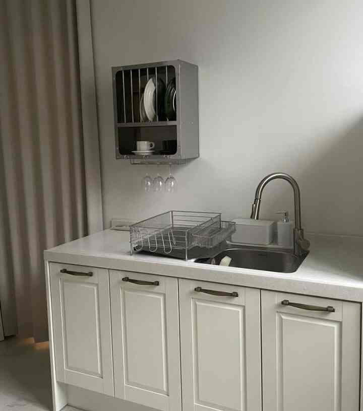 ホワイトとシルバーのトーンのキッチン、マットシルバーの水栓と食器乾燥台が配置された、清潔感のあるモダンなインテリア