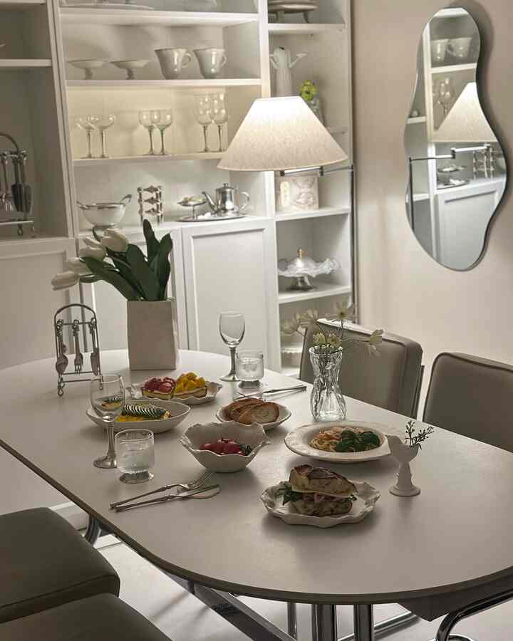 白を基調としたダイニングルーム、マットな陶器の食器とダイニングテーブル、フロアランプが配置された落ち着いた空間