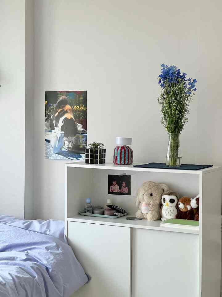 白を基調とした寝室、青い寝具と花瓶、すっきりとした小物が配置された落ち着いたインテリア