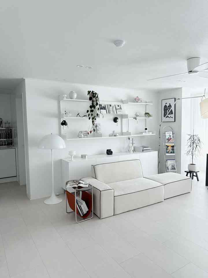 白を基調としたリビングとキッチン、シンプルな2人掛けソファとフロアランプが配置されたモダンな空間