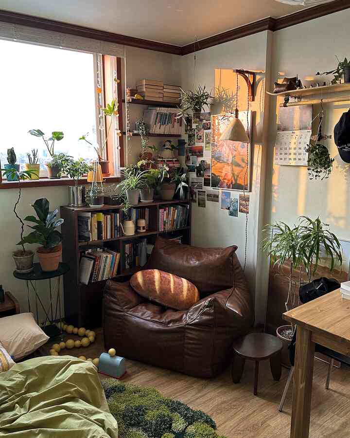 温かみのあるウッドトーンと植物が配置された狭い部屋、ブラウンのレザービーンバッグとグリーンラグが調和した雰囲気のあるインテリア