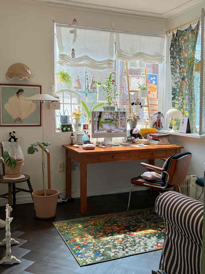 ホワイトと木目調が調和したホームオフィス空間、花柄ラグと多様な植物が配置された陽射しのある雰囲気のインテリア